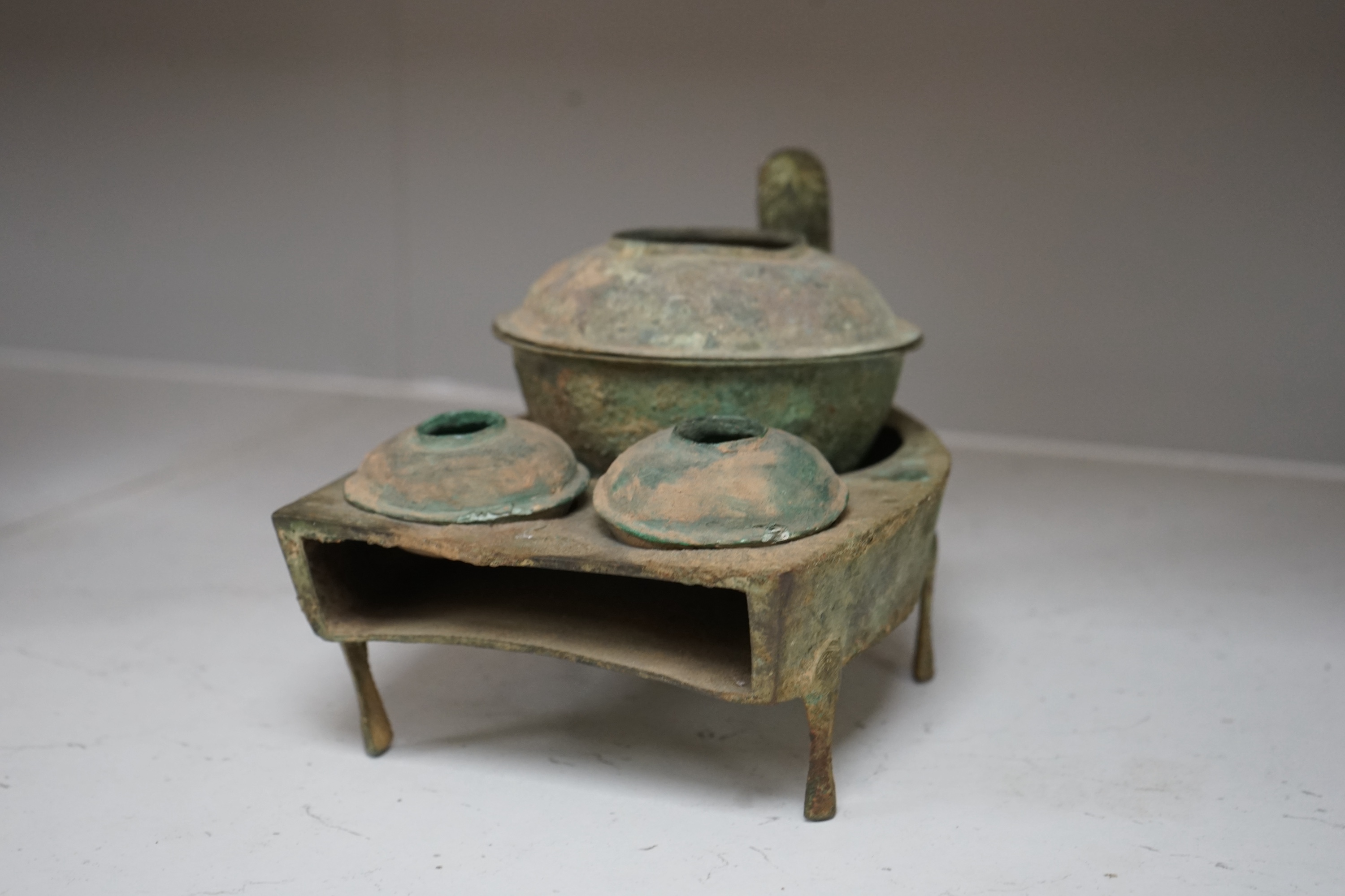 Four Chinese bronze zoomorphic stoves, Han Dynasty, 22cm, together with a Han Dynasty bronze brazier and vessels, width 22.5cm, (5). Condition - poor to fair.